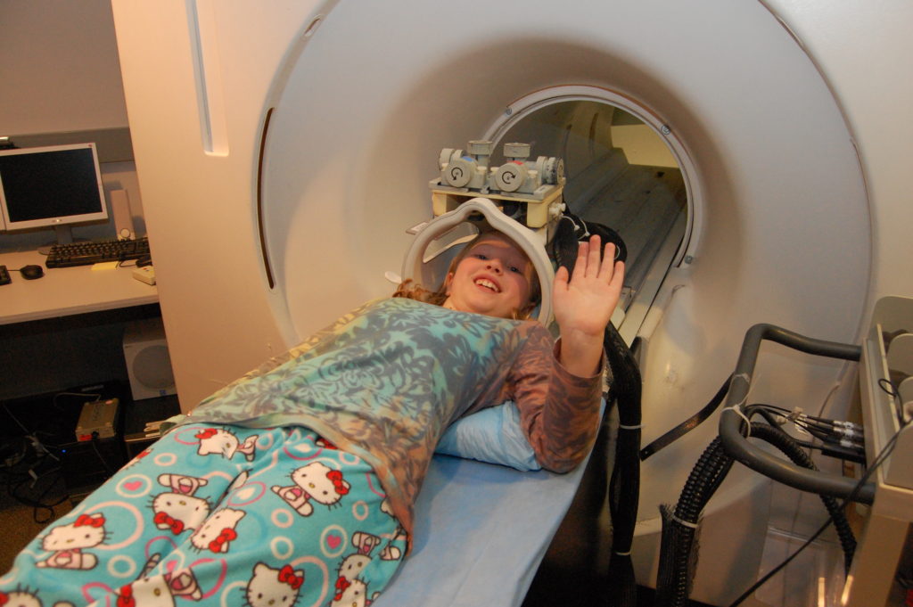 A child waves from the MRI simulator.