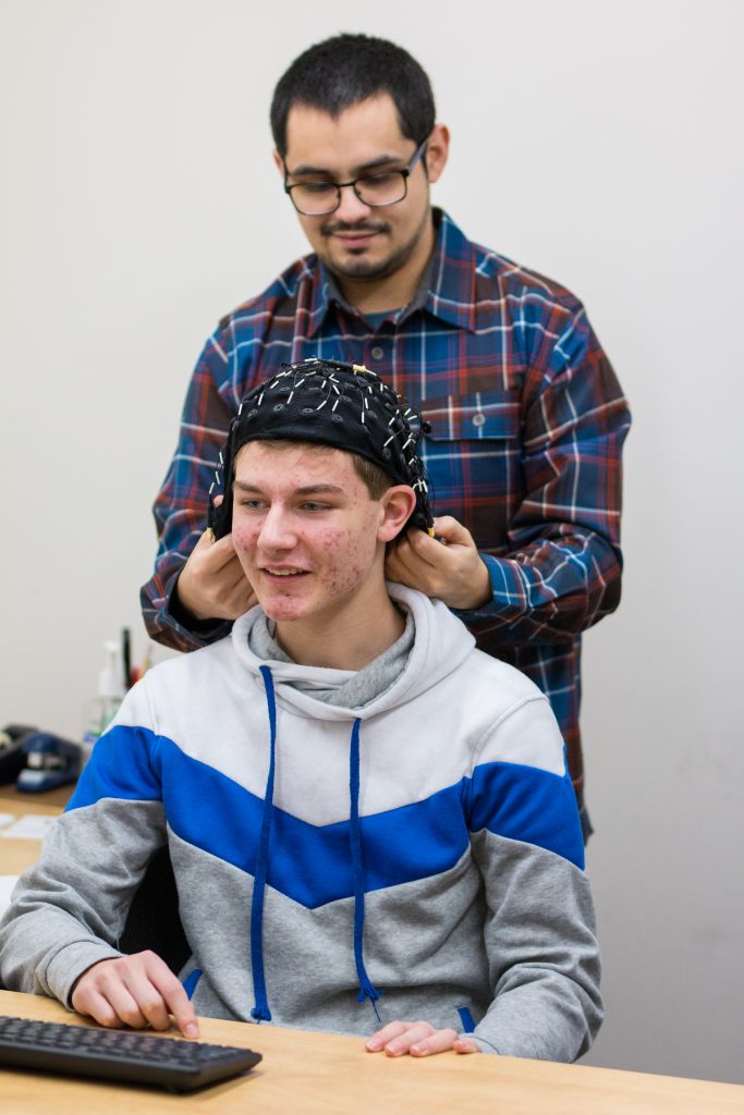 Lab staff adjusts EEG cap on participant